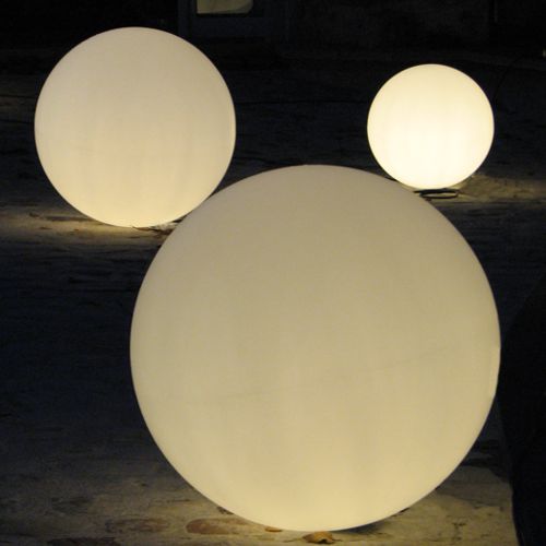 Tres esferas iluminadas en un jardín