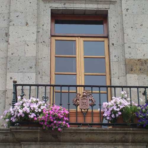 Jardineras con flores en balcon mexicano